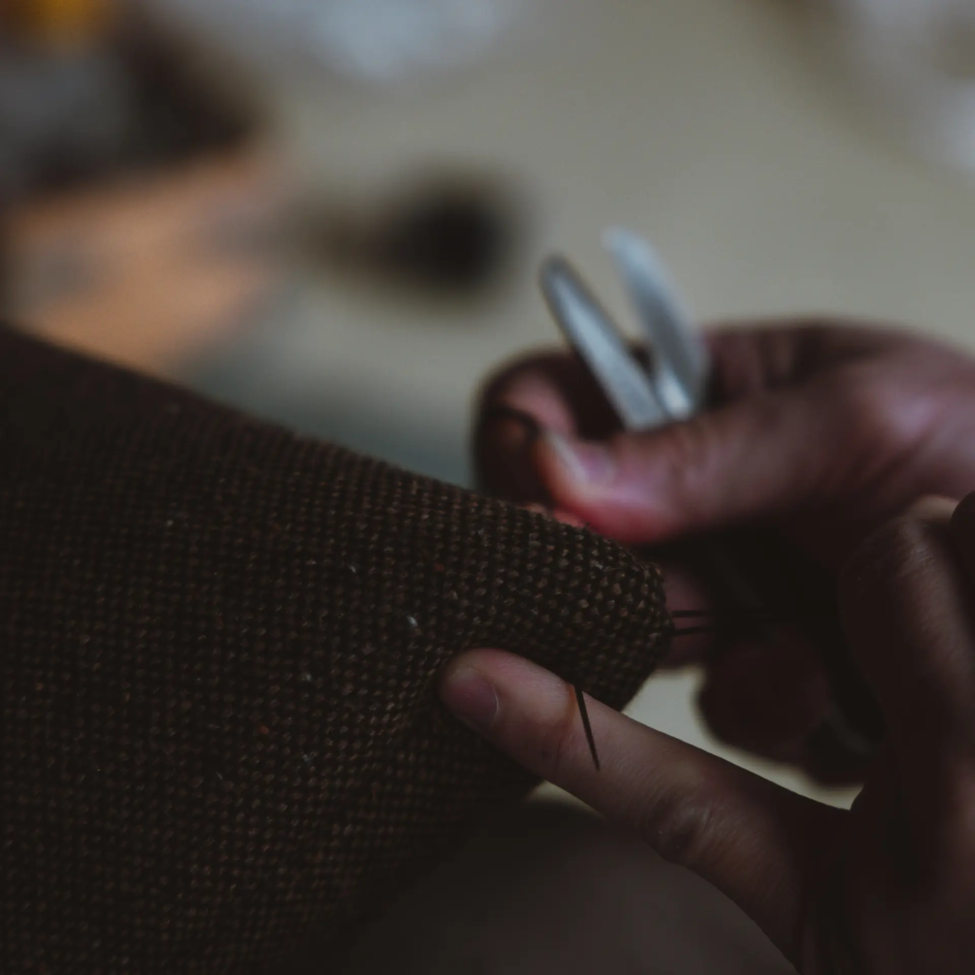 A needle drawn through cloth, close up.