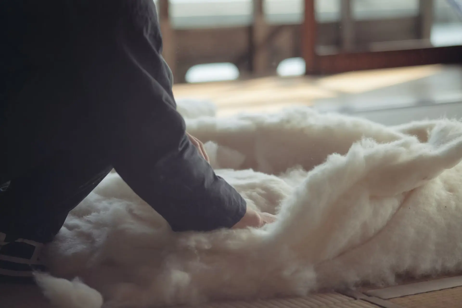 Hands working cotton in the low light of the workshop.