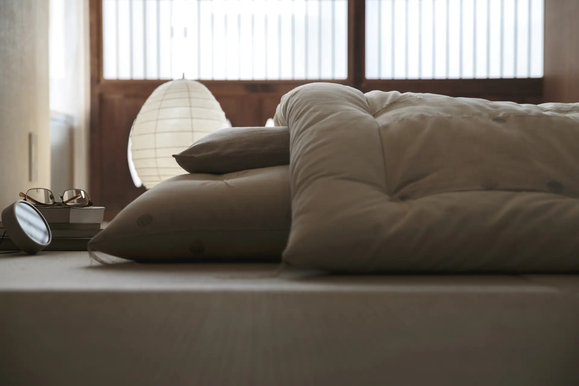 A futon and pillows laid out on a low platform in a bedroom.