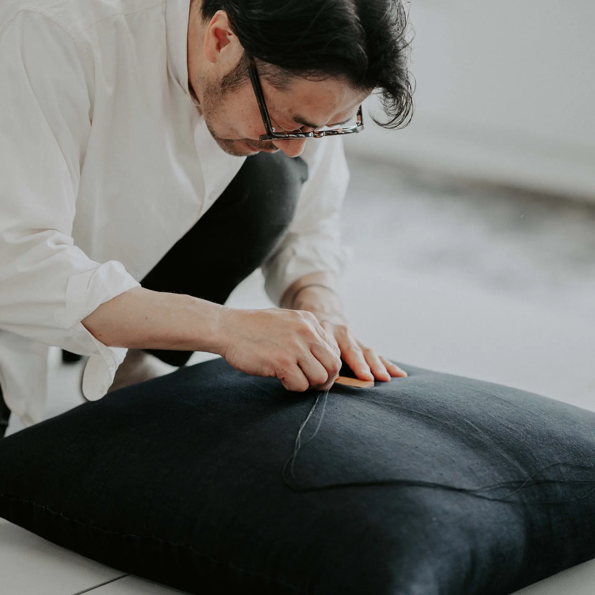 Hand stitching closing the corner of a cushion.