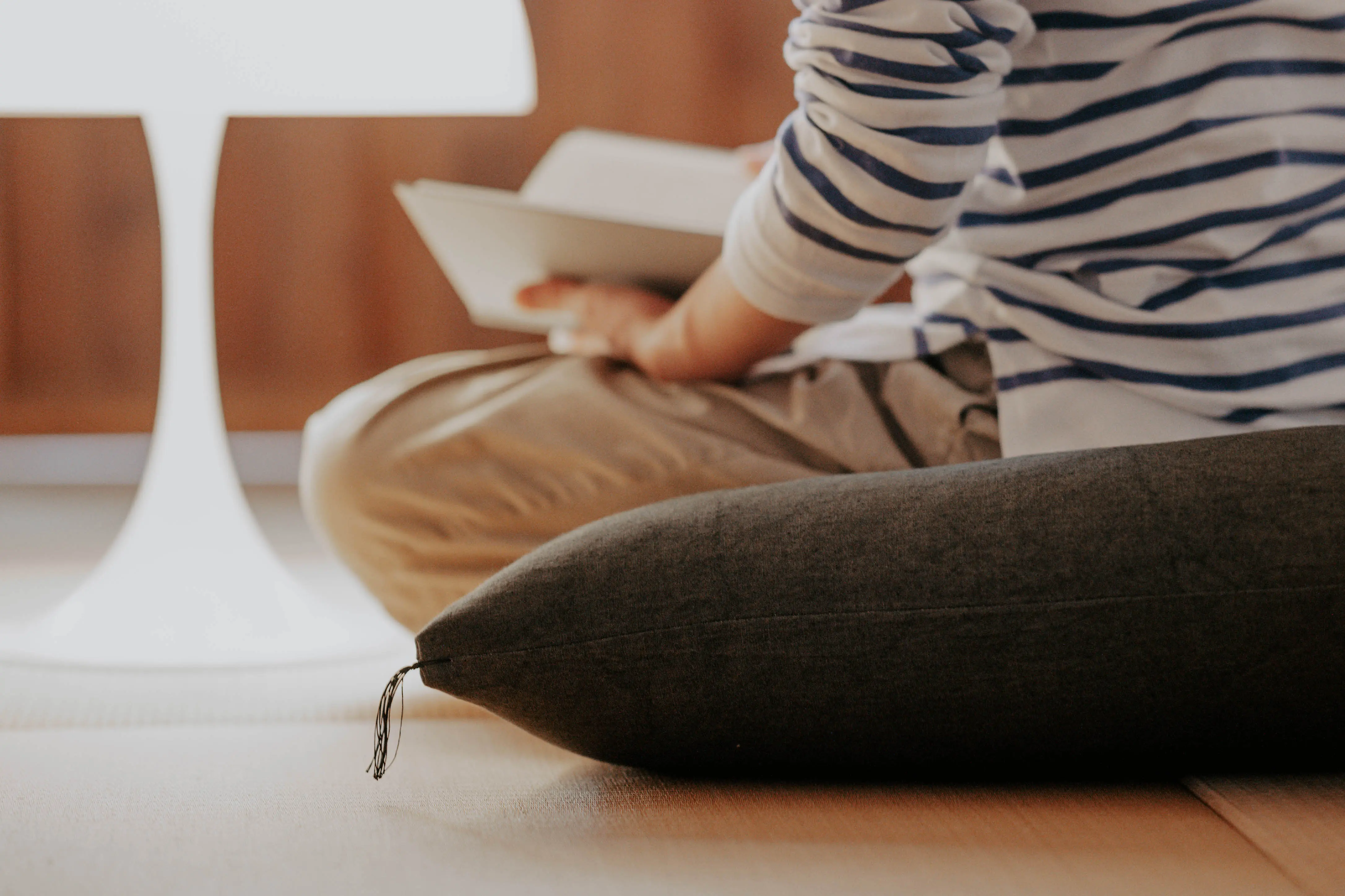 Someone sitting cross-legged on a zabuton, reading.